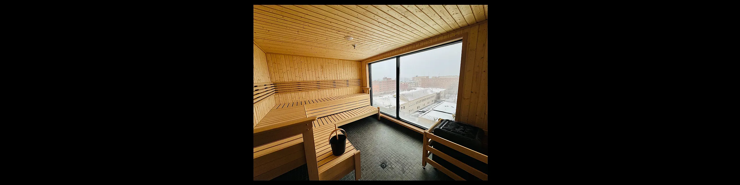 Luxurious sauna with expansive cityscape view, featuring wooden panels and seating for ultimate relaxation.