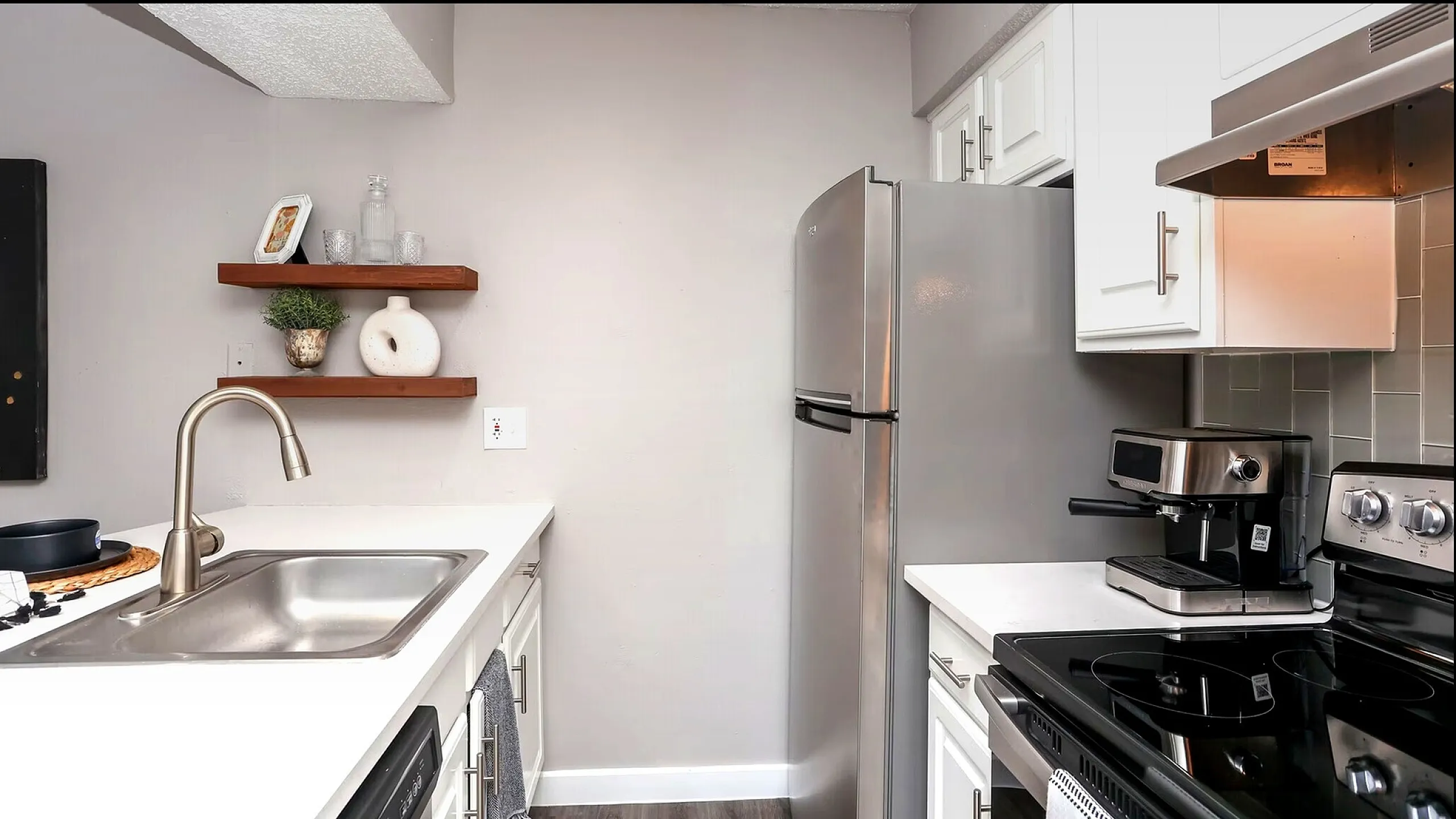 Modern kitchen with stainless steel appliances, sleek countertops, and elegant shelving. Bright and stylish space ideal for culinary creativity.