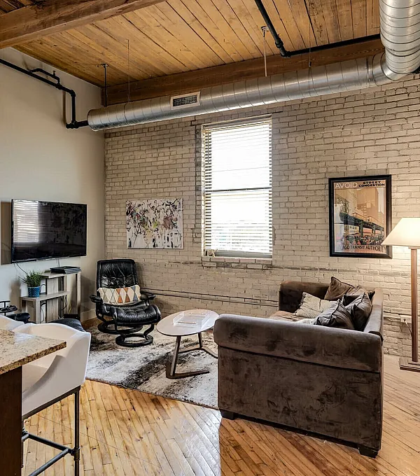 Chic industrial-style living room with exposed brick walls, cozy seating, and a sleek entertainment area.