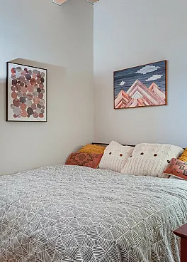 Cozy bedroom with stylish patterned bedding, elegant floor lamp, and vibrant abstract artwork on the walls.