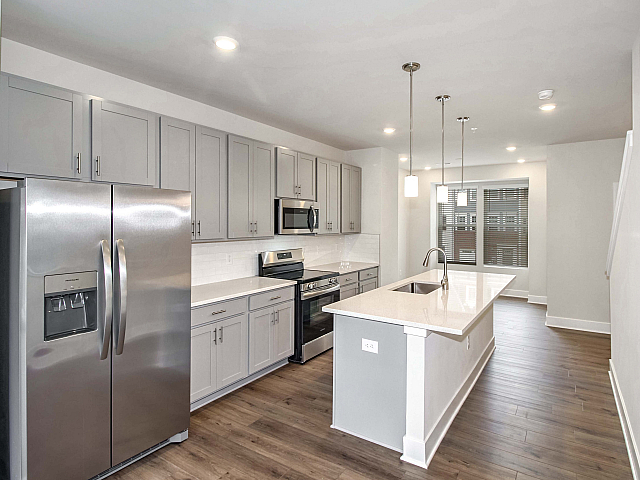 Sleek modern kitchen with stainless steel appliances, elegant pendant lighting, and spacious quartz countertops.