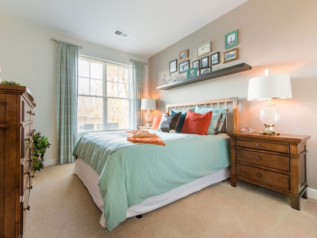 Spacious bedroom with a large window and carpeting at Prospect Hall Apartments