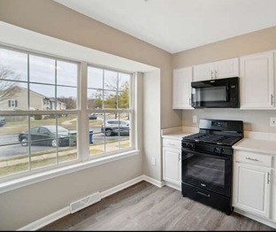 Renovated kitchen at 6306 Jacobs Court with white cabinets, black appliances