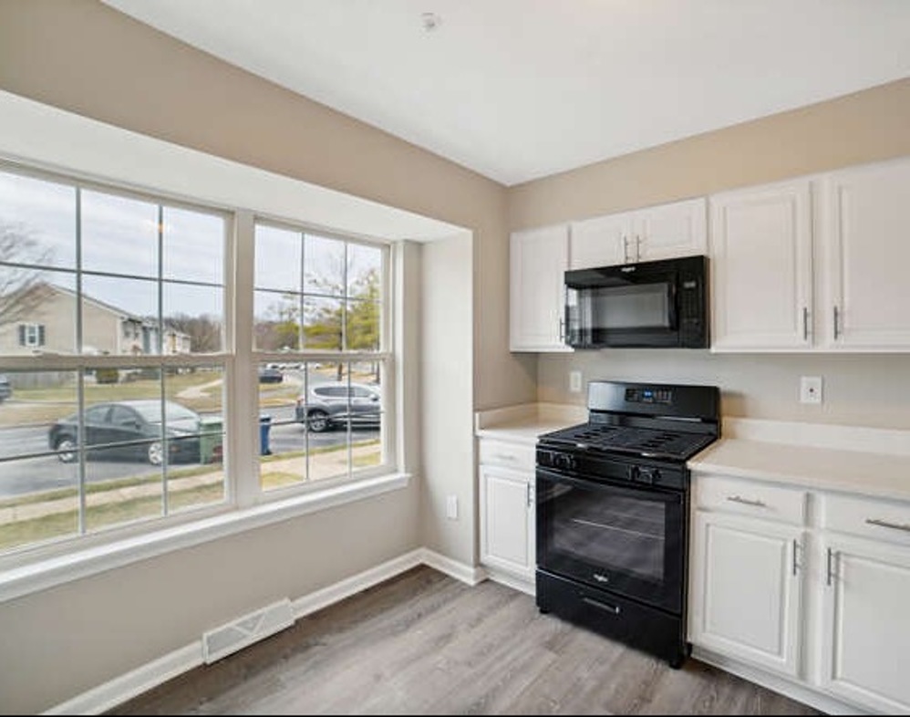 Renovated kitchen with white cabinets, black appliances, and large windows at 6306 Jacobs Court.
