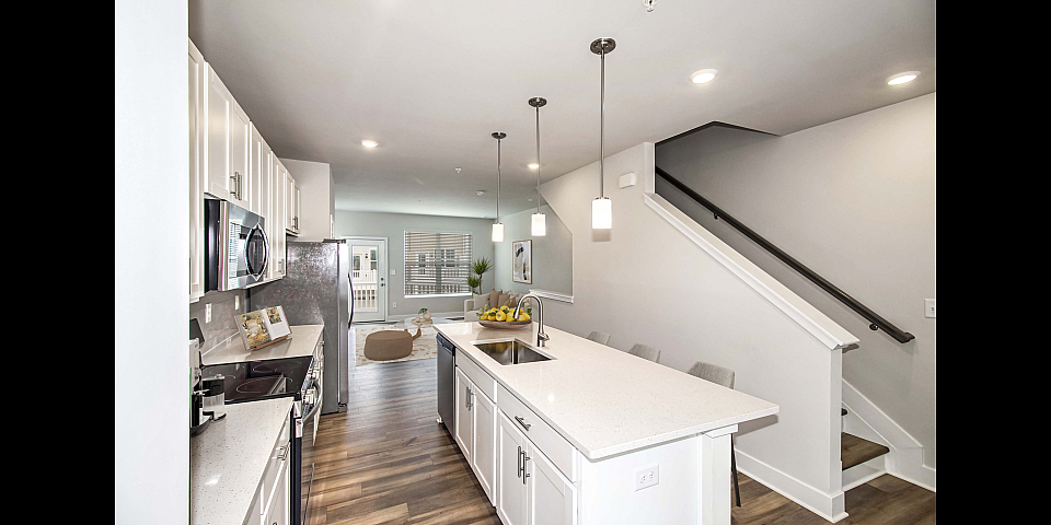 Stylish kitchen with a large island, contemporary appliances, and open flow to a bright living area.