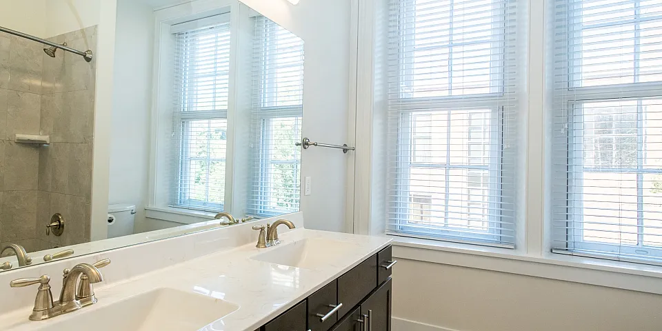 Elegant bathroom featuring a stylish double vanity with marble countertop, large mirror, and abundant natural light from oversized windows.
