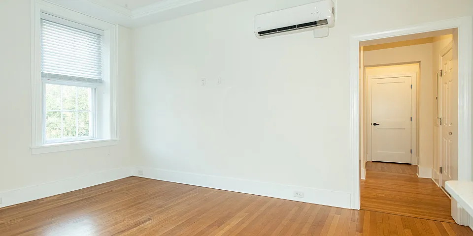 Bright living room with hardwood floors, large windows, and ceiling fan.