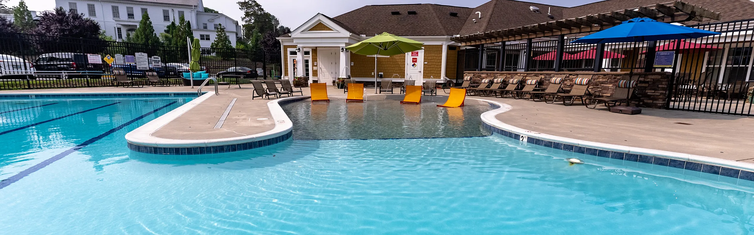 Inviting pool area with vibrant lounge chairs and shaded seating, perfect for relaxation under clear skies.