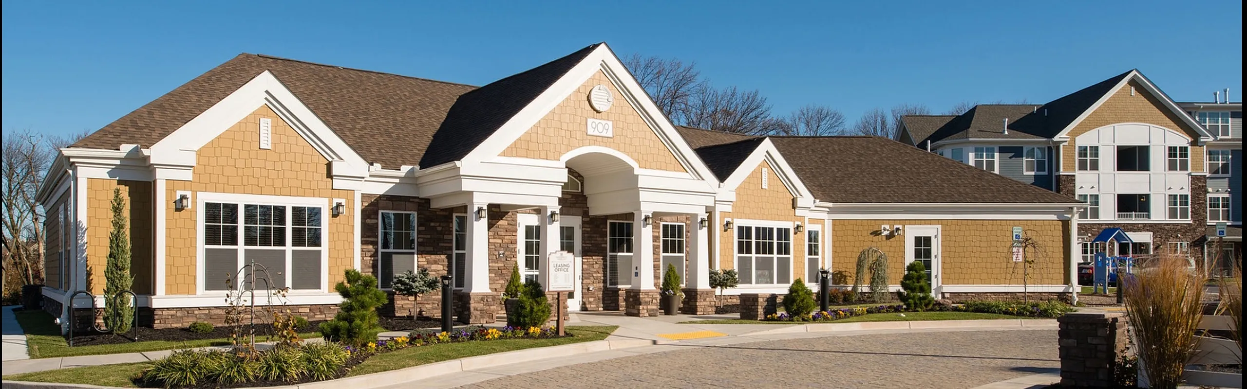 Charming residential community entrance with modern architecture, manicured landscaping, and welcoming pathways.