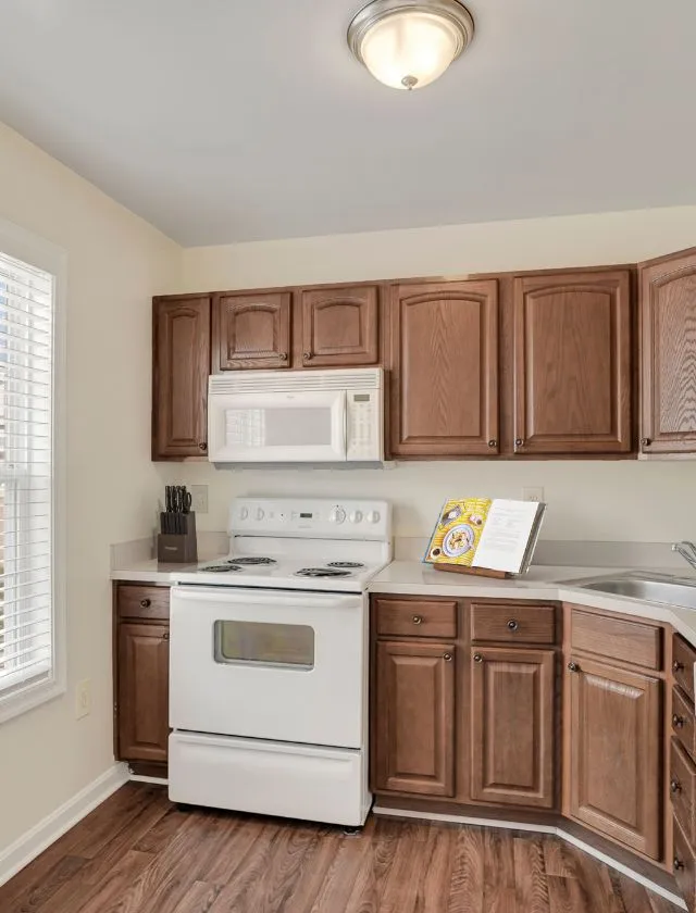 Charming kitchen with elegant wooden cabinets, modern white appliances, and warm natural lighting.