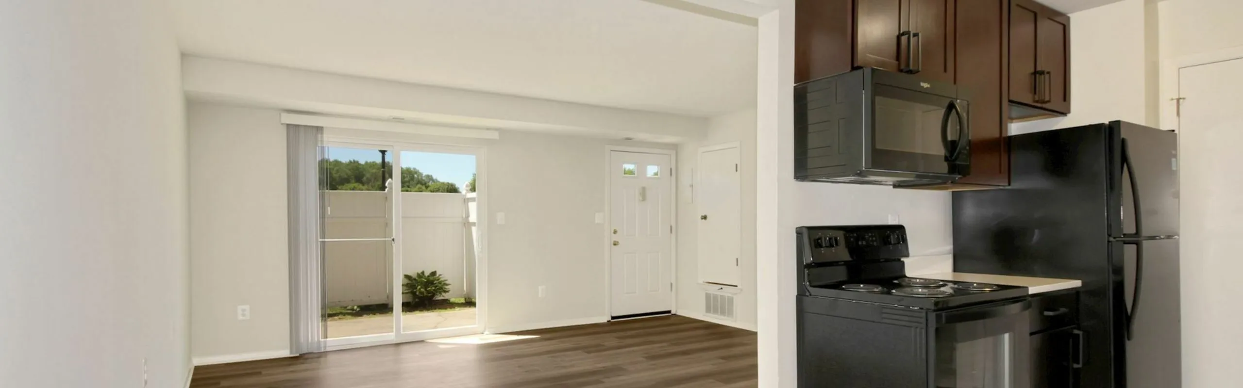 Charming open-concept living and kitchen area with sleek appliances and bright sliding doors opening to a cozy outdoor space.