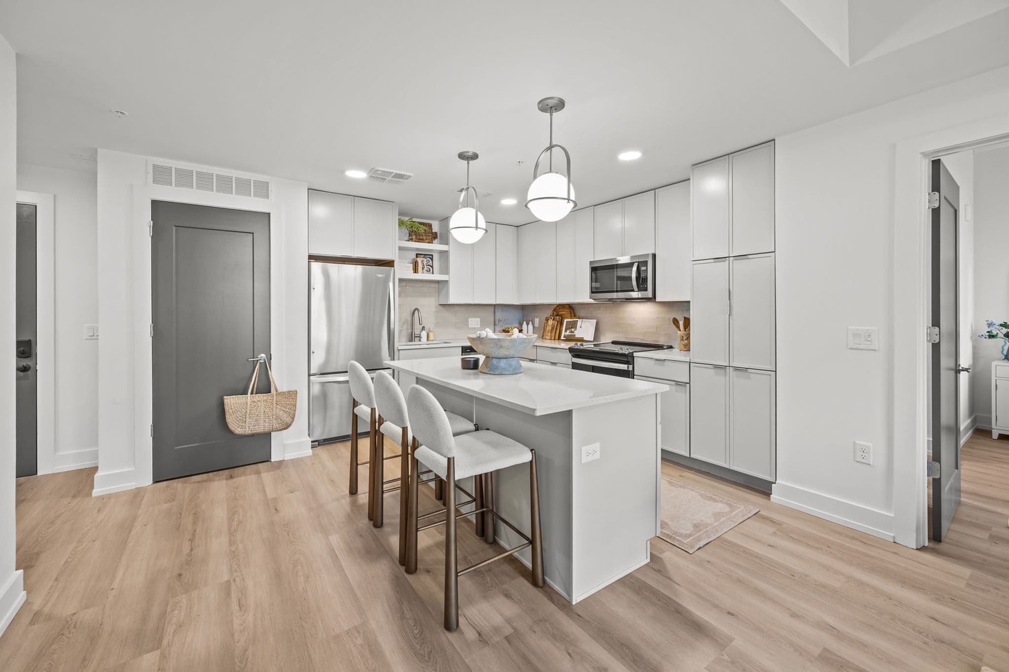 Modern kitchen with sleek white cabinetry, stainless steel appliances, and a central island with cozy seating.