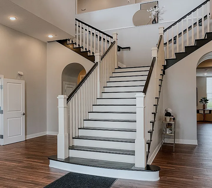 Grand staircase with modern wooden flooring and open access to a fitness room.