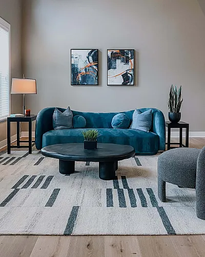 Modern living room with a plush teal sofa, elegant abstract artwork, and a sleek coffee table, creating a stylish and inviting atmosphere.