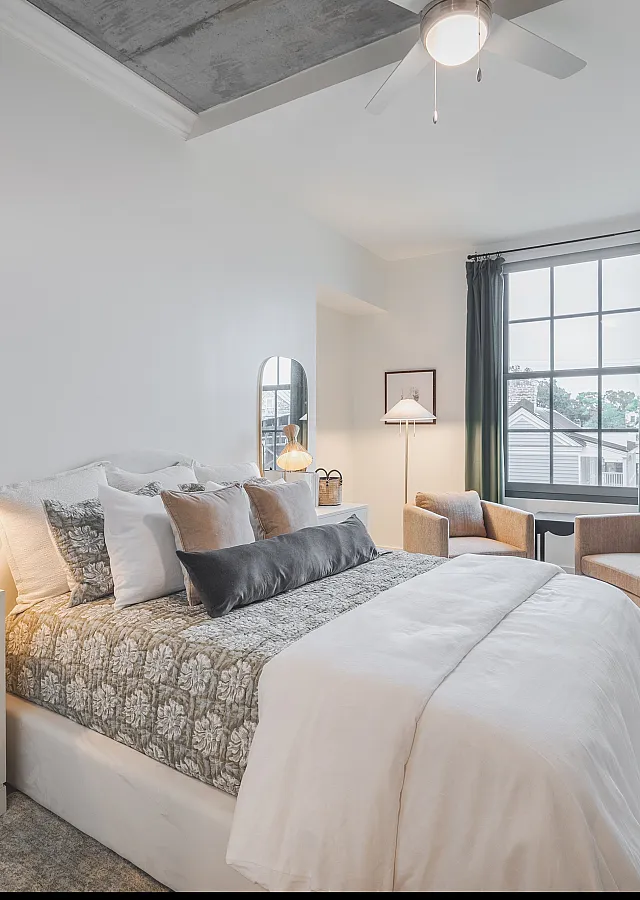 Elegant bedroom with natural light, featuring a cozy bed, stylish nightstand, and chic decor.