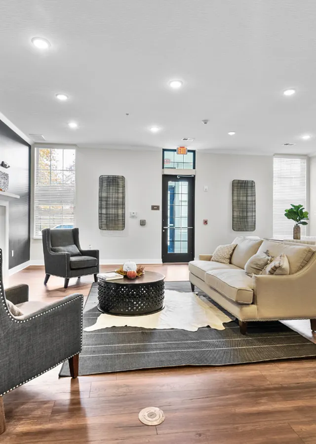 Elegant living room with cozy sofa, stylish armchairs, and a chic round coffee table on a plush rug, offering a warm and inviting ambiance.