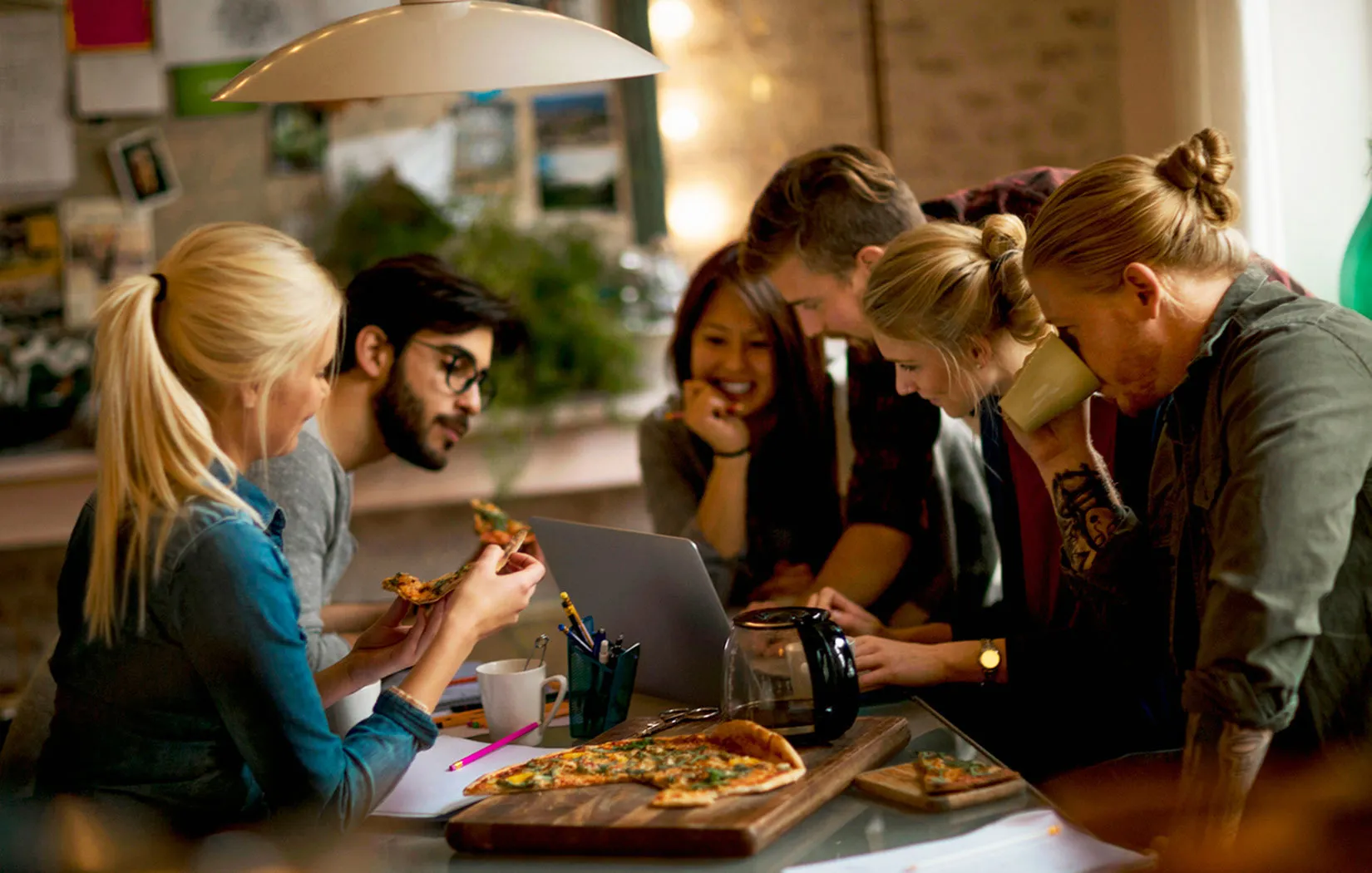 Cozy and inviting workspace filled with creativity, featuring a group of people enjoying pizza and brainstorming together.