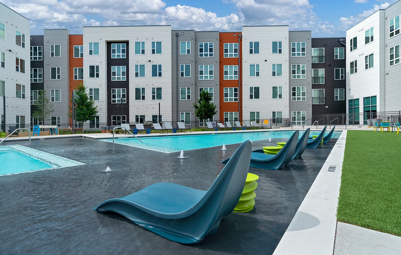 Modern apartment complex featuring a stunning outdoor pool area with sleek lounge chairs and vibrant architecture.