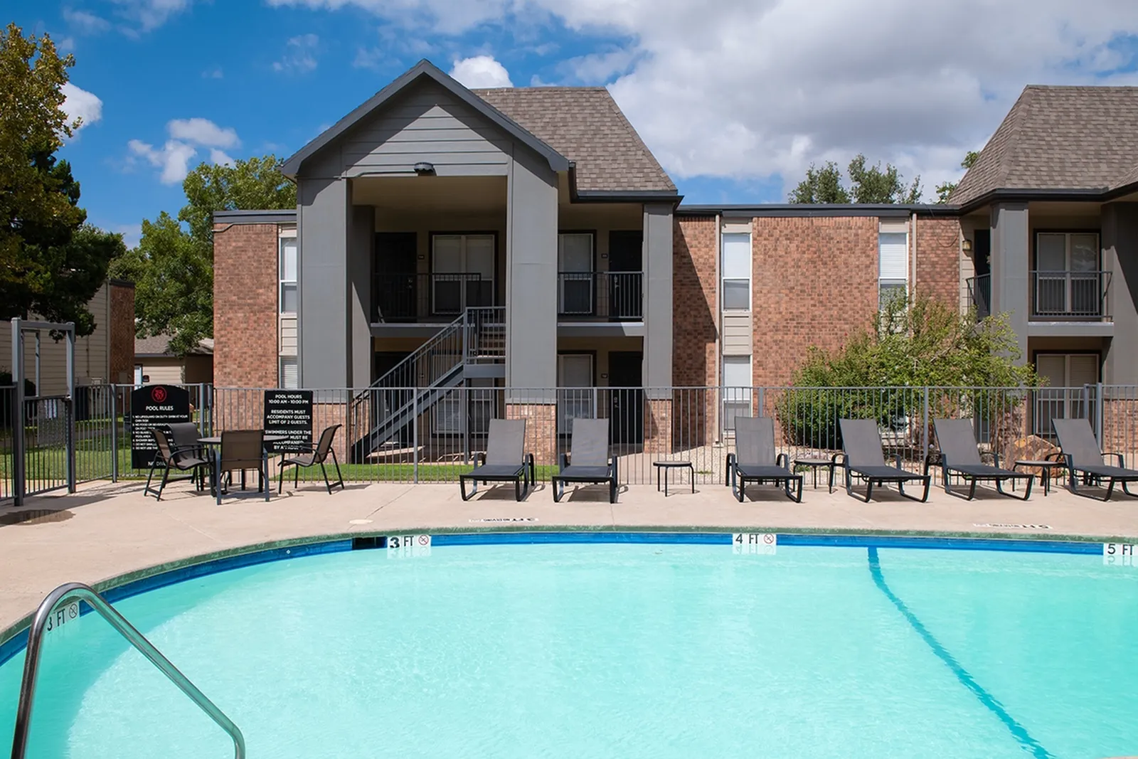 Community pool with sun chairs in front of apartments