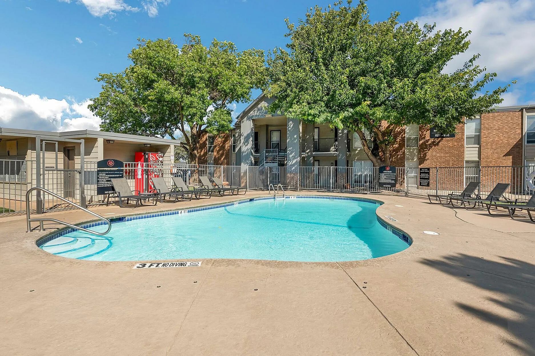 Community pool with sun chairs in front of apartments