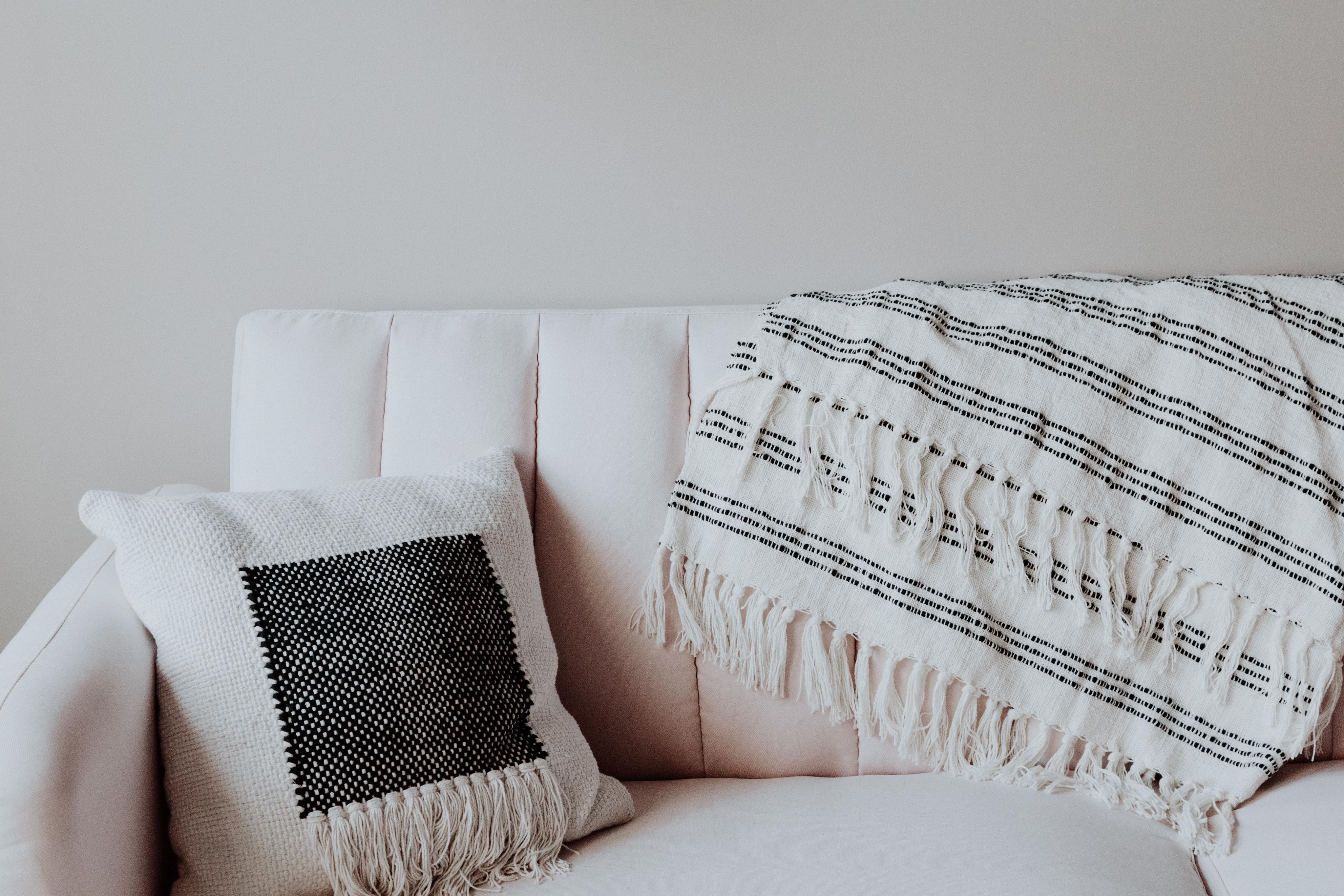 white couch with throw blanket and throw pillow