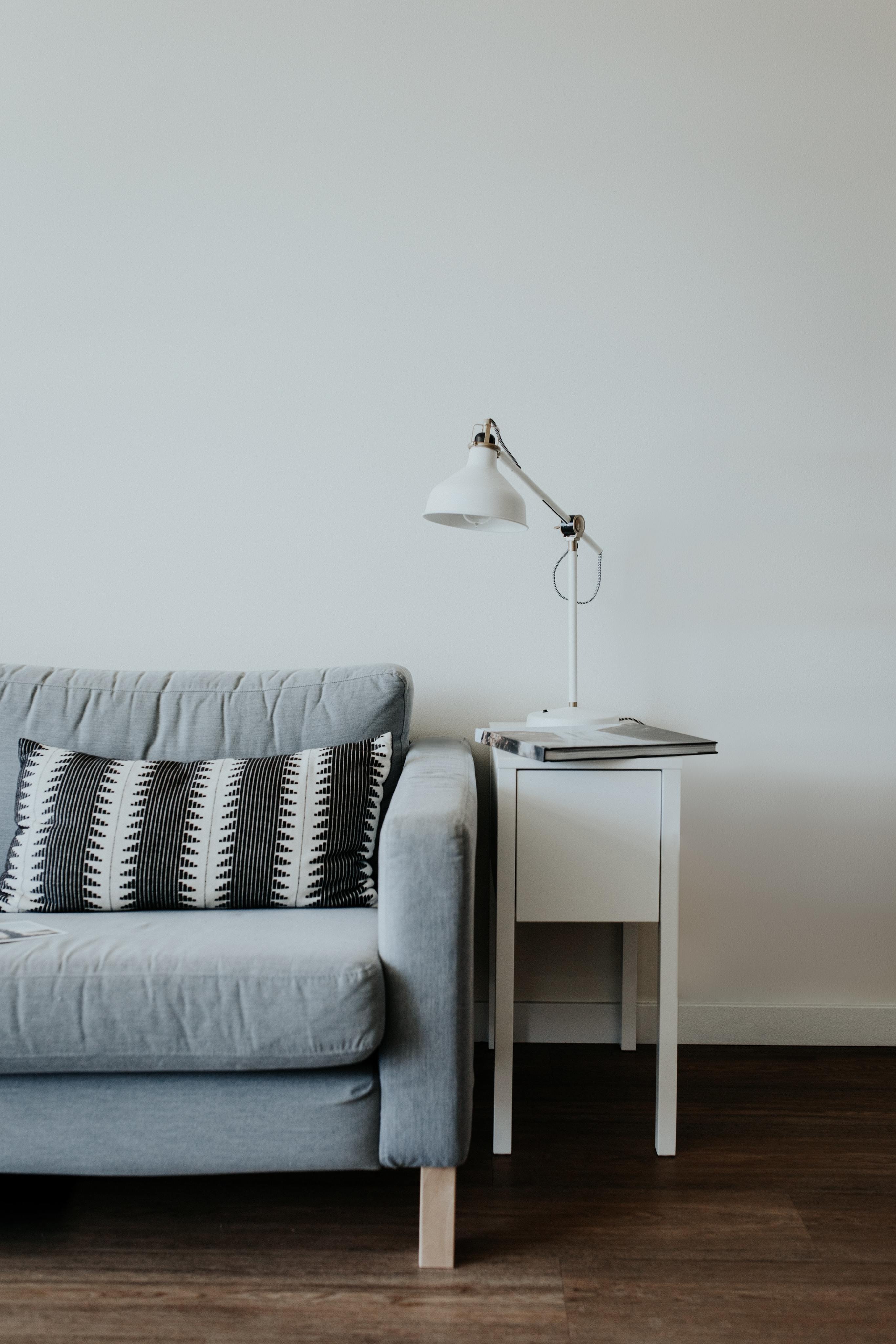 grey couch with throw pillow. side table and lamp on right side.