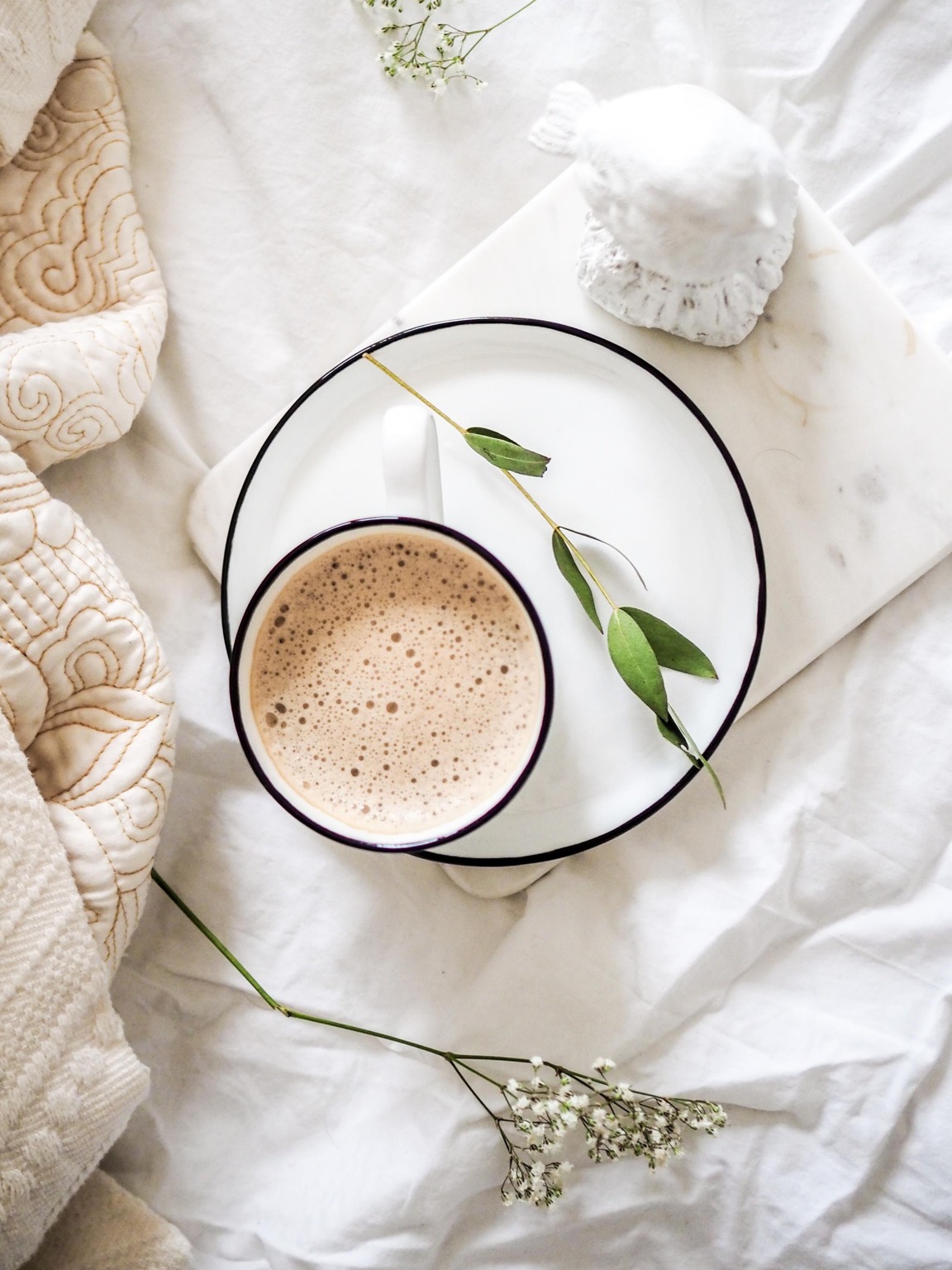 cup of coffee on a plate on top of linens