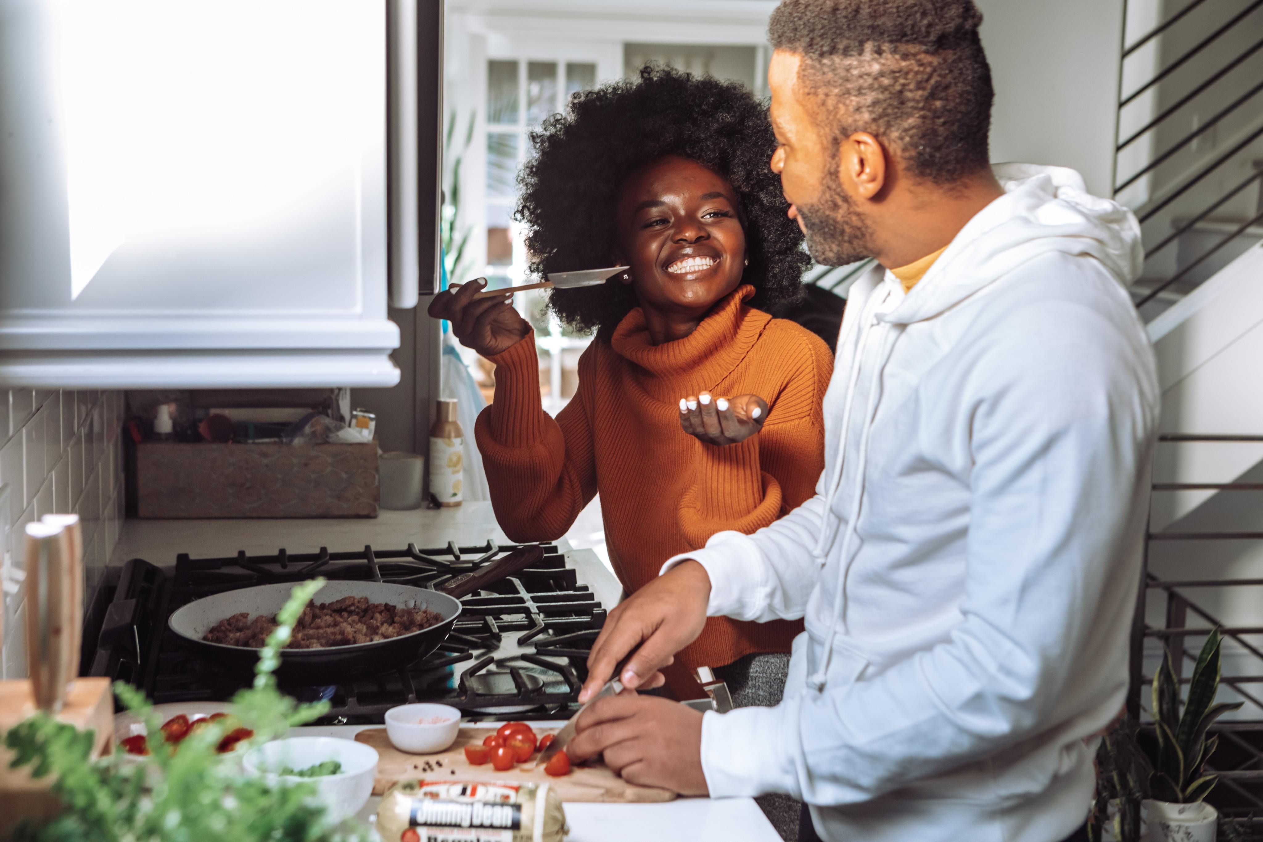 friends tasting their cooked meal at the stove