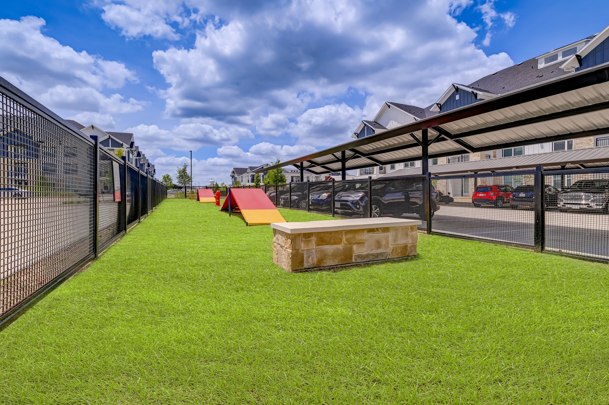 Fenced in dog run with agility course and seating