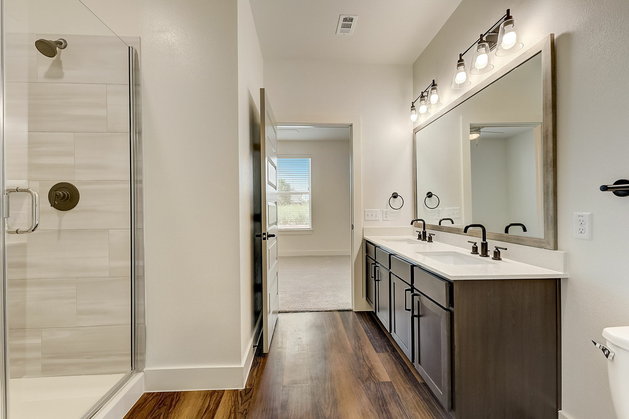Bathroom with dual vanity, stand-up shower, and quartz countertops