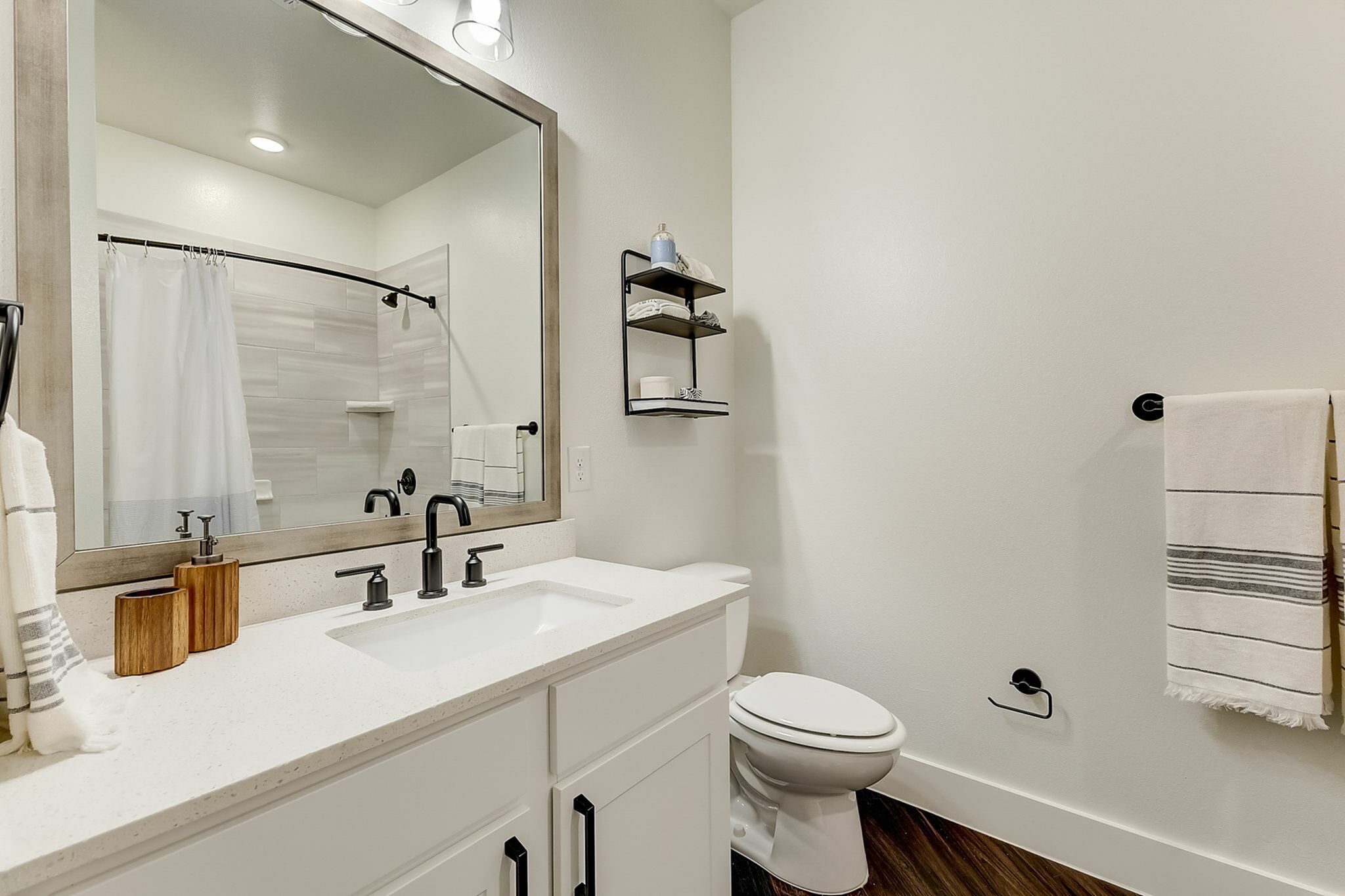 Bathroom with white cabinetry, quartz countertops, and black plubming features