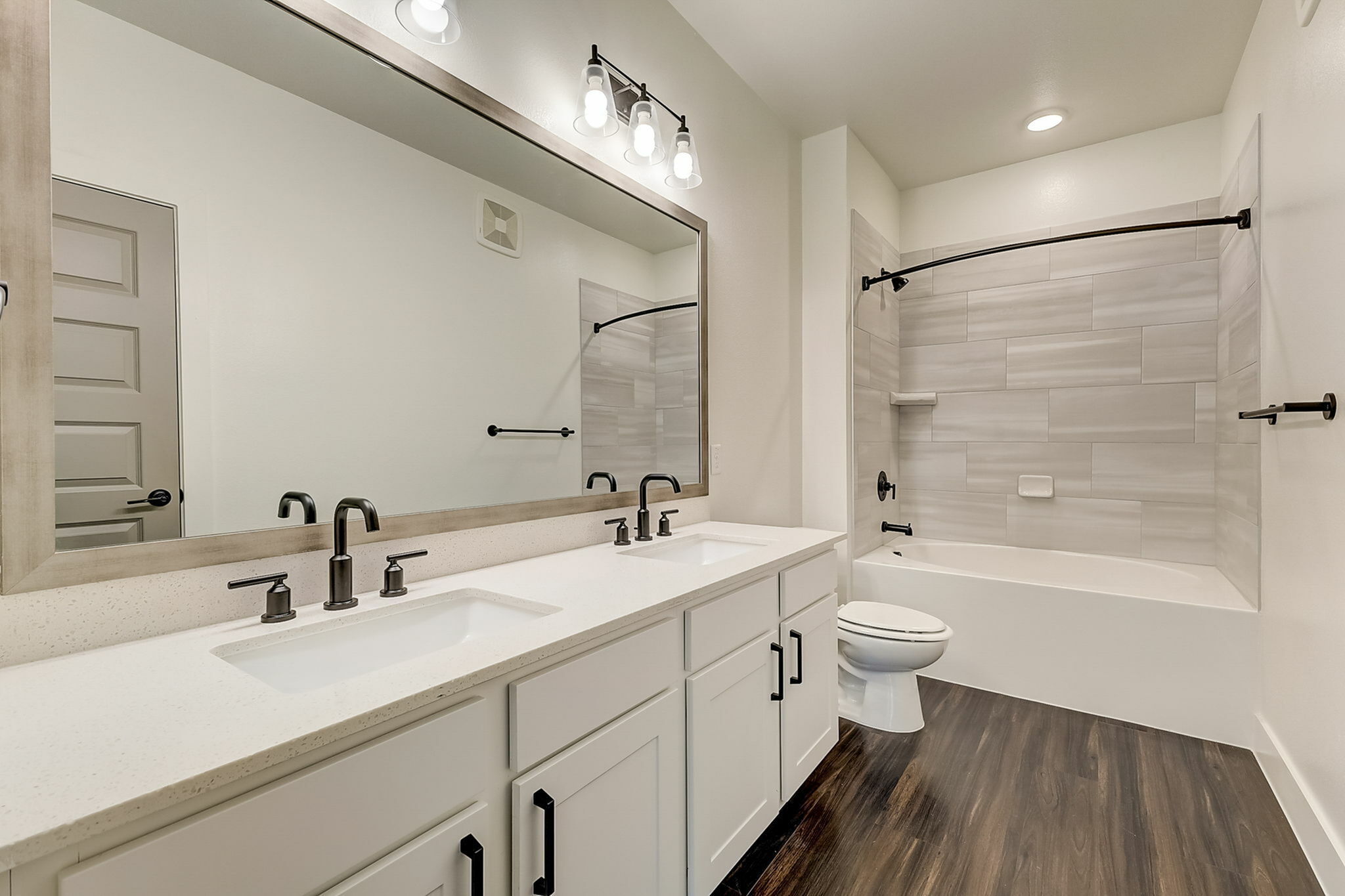 Bathroom with double vanities, garden tub, hardwood-style flooring