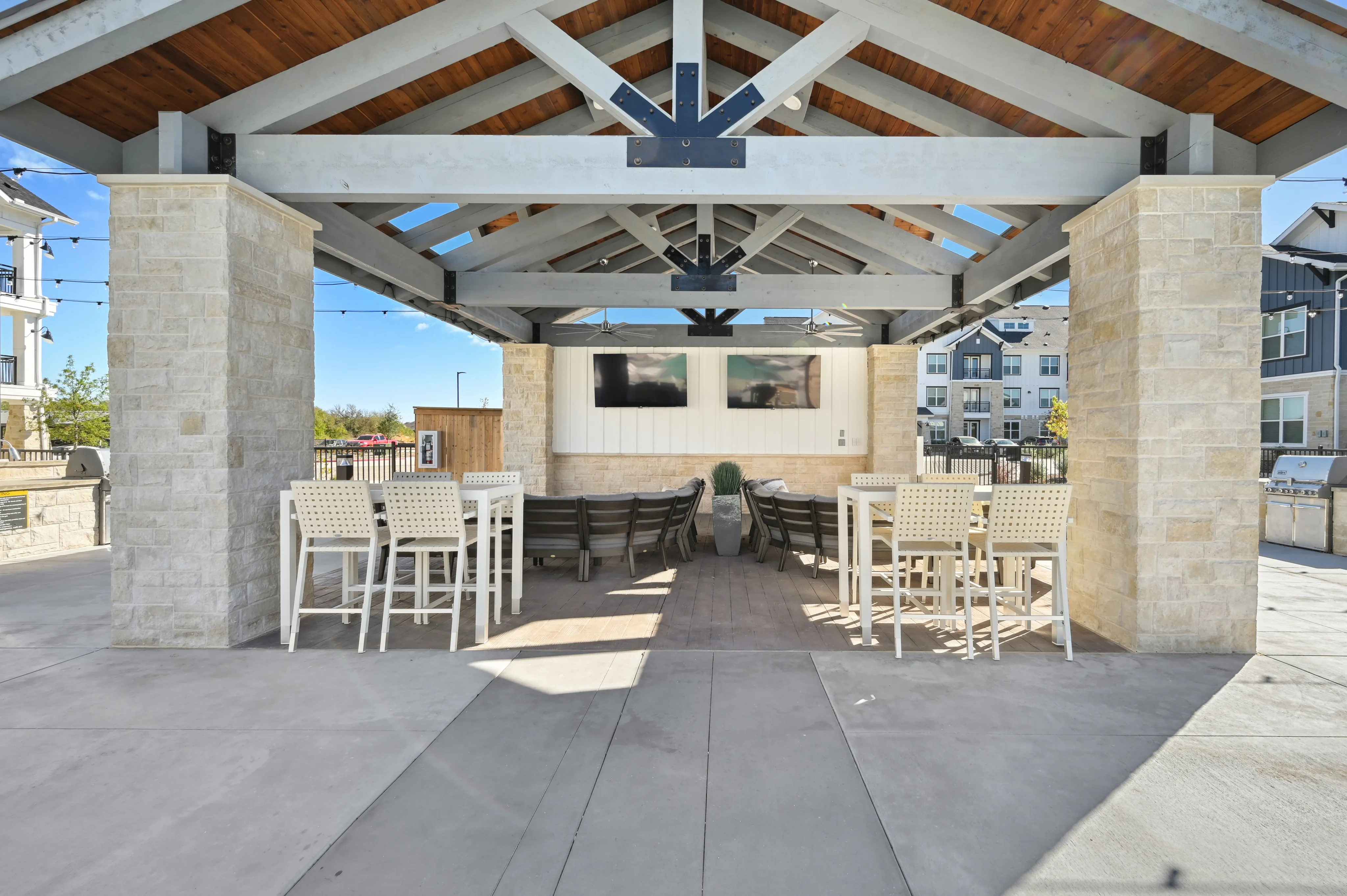 Covered outdoor seating area with grills and TV