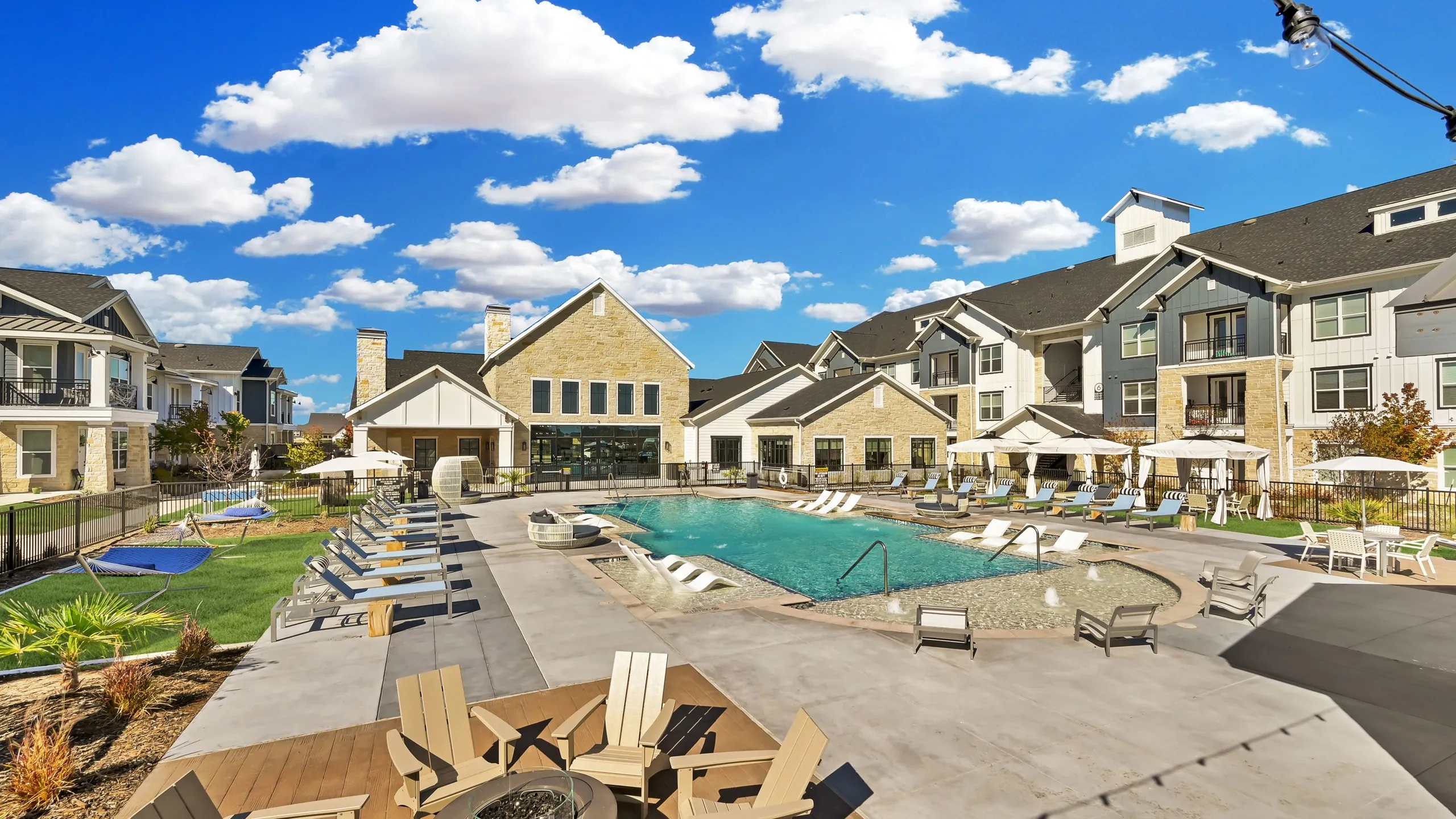 Resort-style pool with lounge chairs, fire pit, and tables