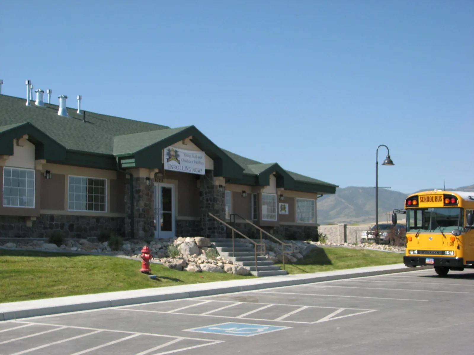 Charming educational facility exterior with green roofing and a welcoming school bus.