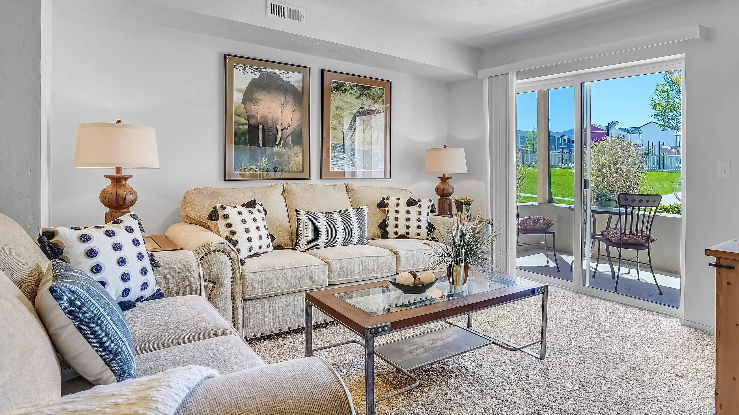Bright living room with beige sofas, artistic animal decor, and a glass coffee table.