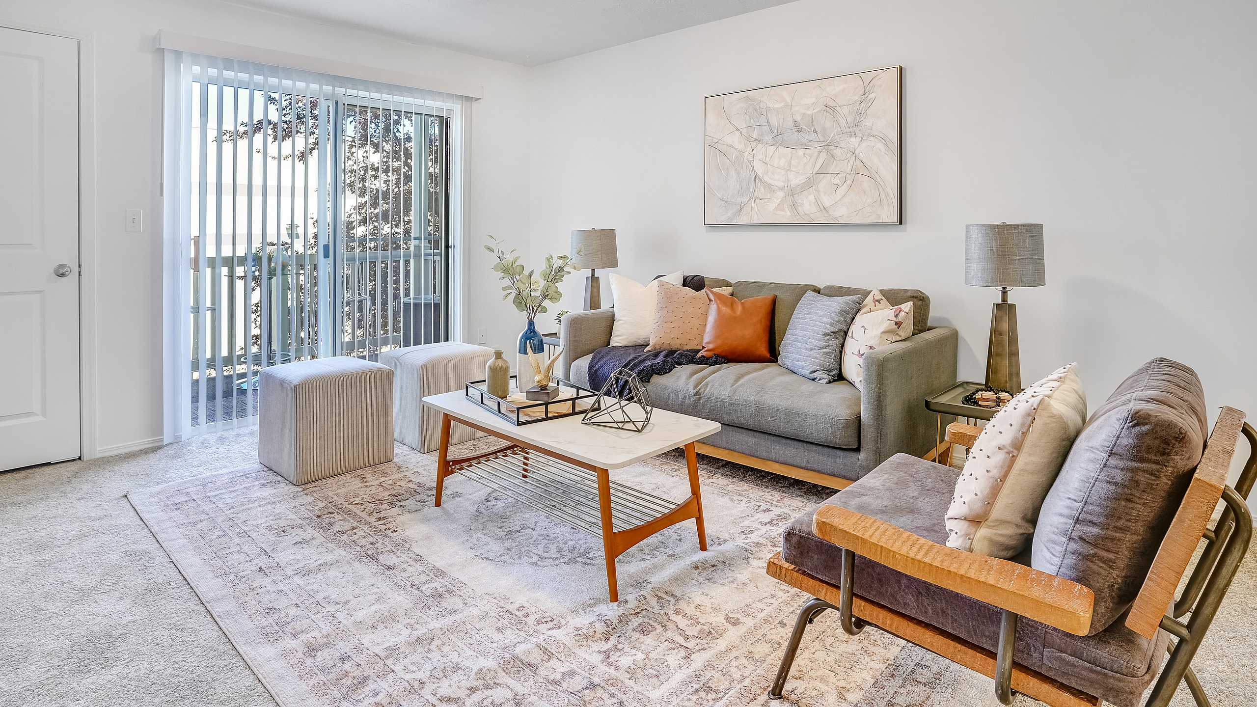Bright, modern living room with stylish decor, spacious sofa, art piece, and natural light through sliding doors.