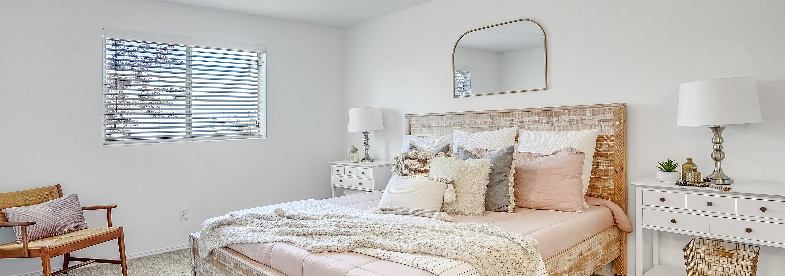 Inviting bedroom with a plush bed, neutral decor, natural light, and stylish furnishings.