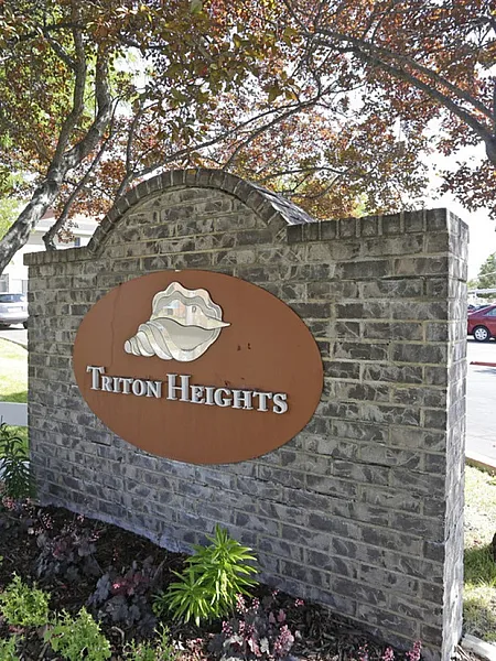Entrance sign of Triton Heights surrounded by lush greenery.