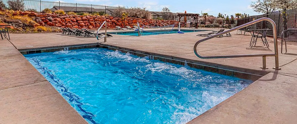 Luxurious outdoor pool area with crystal-clear water, surrounded by elegant lounge chairs and scenic views of natural stone landscaping.
