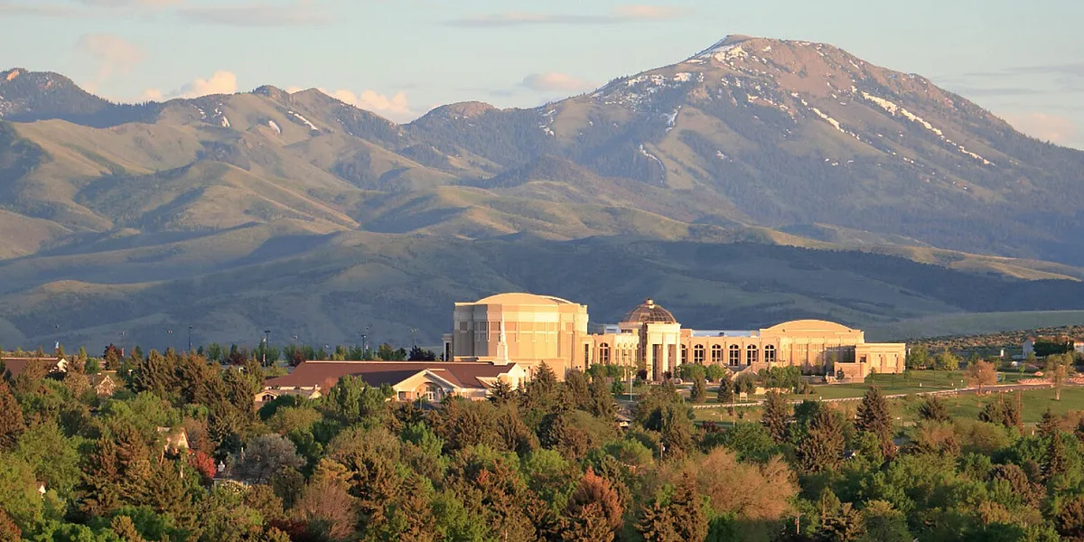 Stunning complex nestled at the base of majestic snow-capped mountains surrounded by lush greenery, offering a serene and picturesque setting.