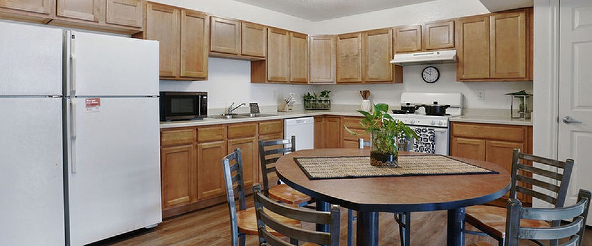 Bright and welcoming kitchen with modern wooden cabinetry, large refrigerator, and a cozy dining area for family gatherings.