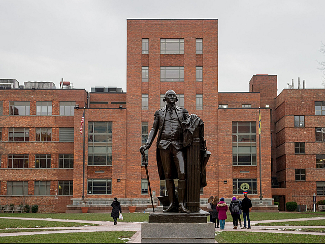 Impressive brick building with a prominent statue in front, showcasing classic architecture and a spacious courtyard.