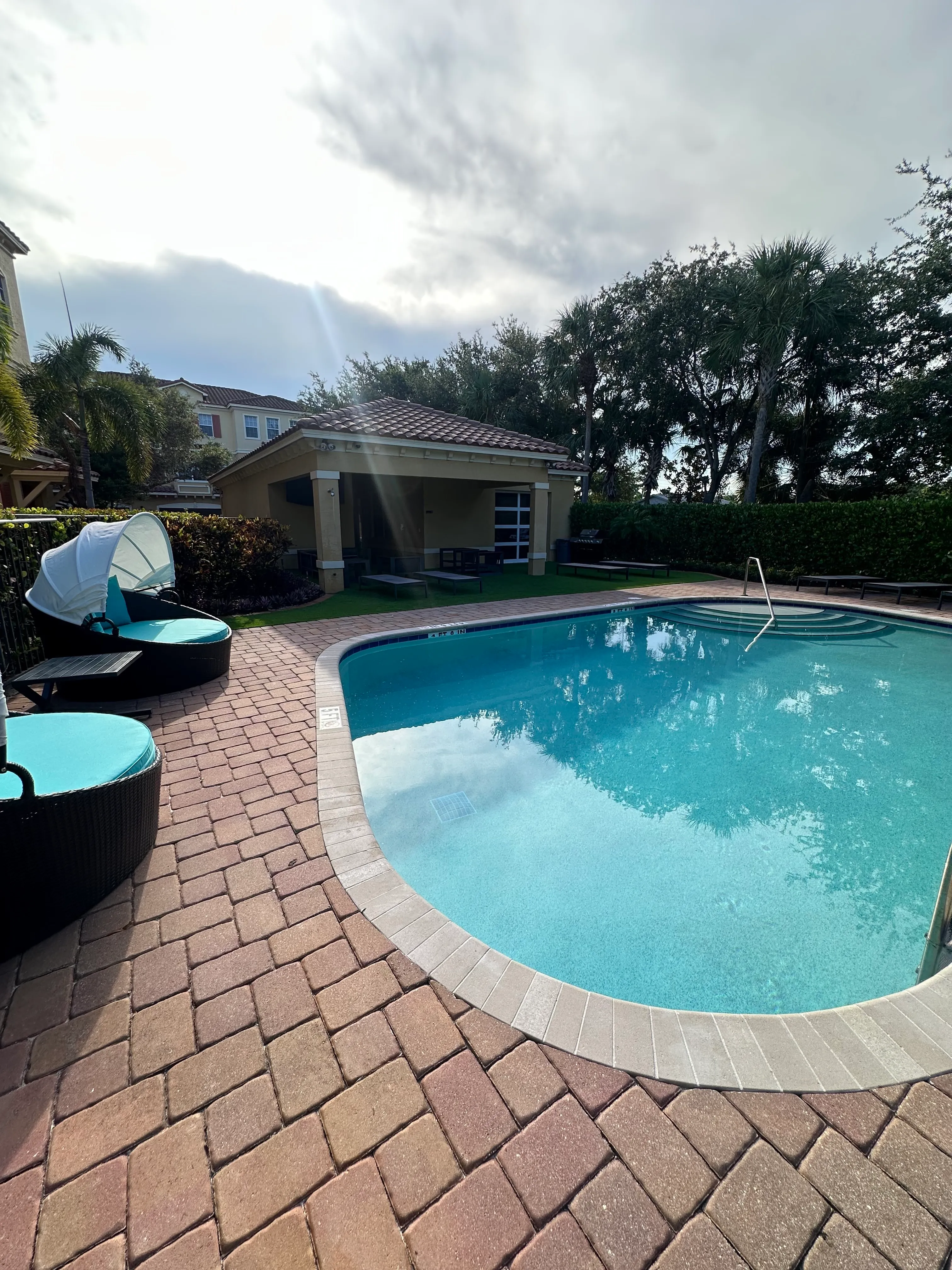 Luxurious outdoor area with a sparkling pool, cozy lounge chairs, and lush greenery, perfect for relaxation and enjoyment.