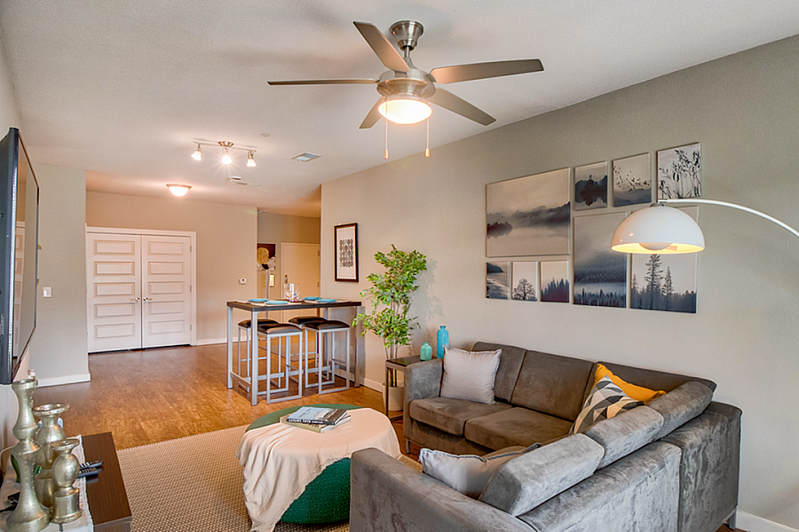 Bright and modern living room with a cozy sectional sofa, elegant decor, and chic bar stool seating, perfect for entertaining.