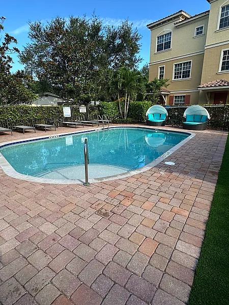 Charming apartment complex pool area with inviting lounge chairs, lush greenery, and modern architecture.