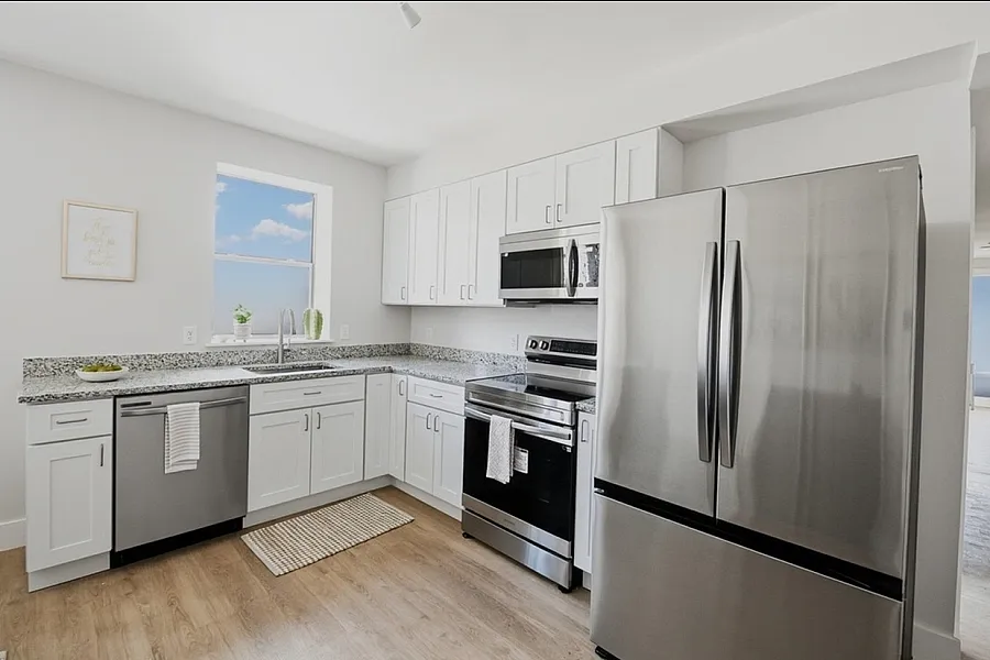 Bright and modern kitchen with sleek stainless steel appliances, elegant white cabinets, and a spacious granite countertop.