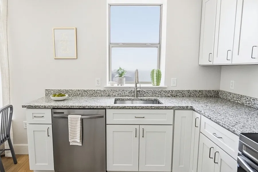 Modern kitchen with granite countertops, sleek cabinets, and stainless steel appliances, beautifully illuminated by natural light.