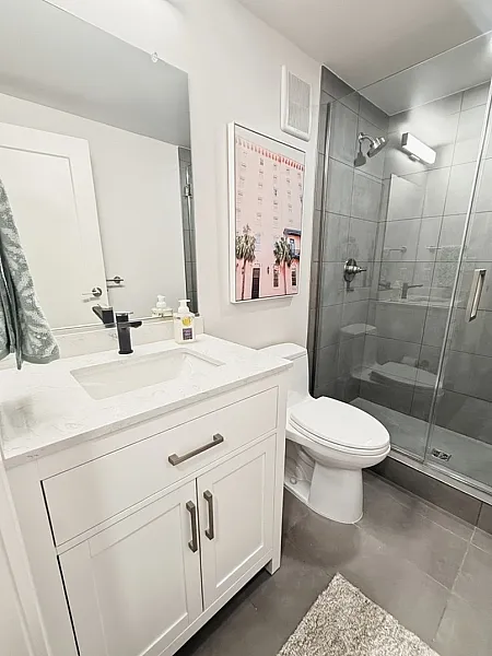 Modern bathroom with sleek glass shower, elegant white vanity, and stylish decor.