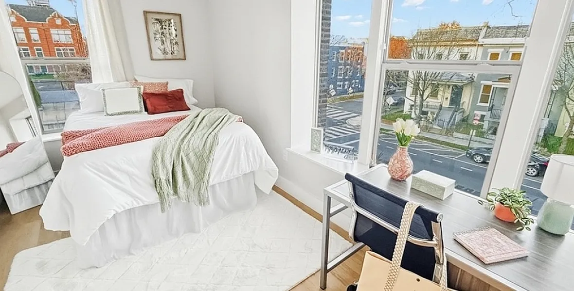 Bright and cozy bedroom with a large bed, stylish decor, and expansive windows offering a stunning city view. Perfect blend of comfort and urban living.